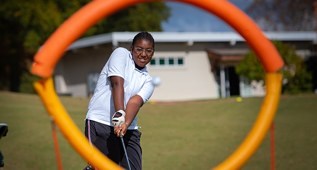 Child putting a golf ball through a hoop