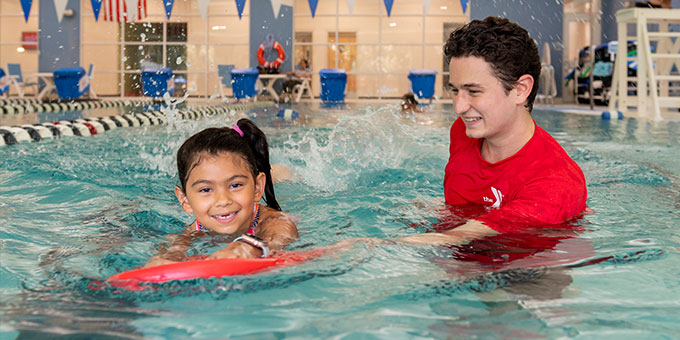 Child learning to swim with instructor