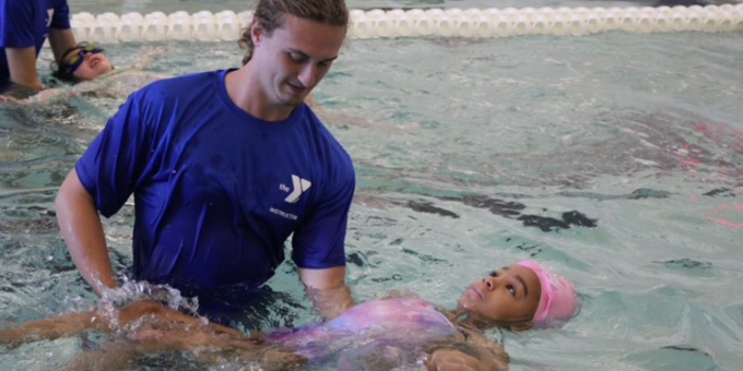swim instructor teaching a girl to float on her back