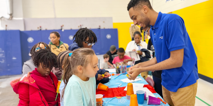 camp counselor helping children at a table