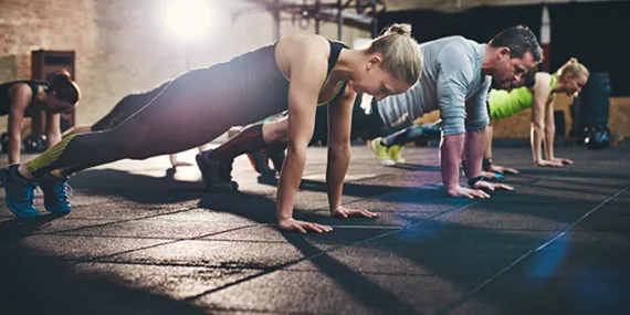 three people lined up doing a push up