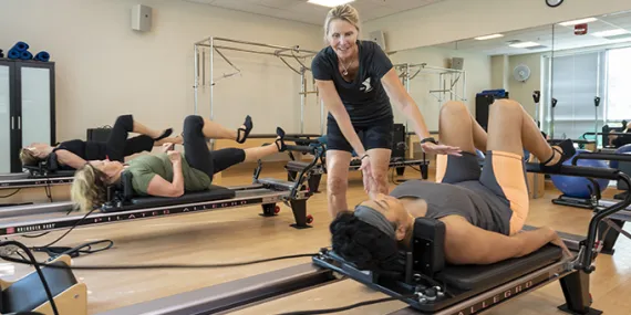 Instructor helping someone on a Pilates reformer