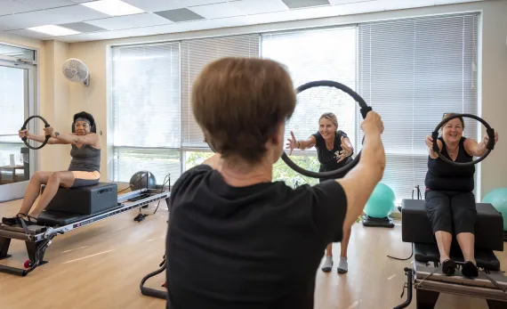 Three women doing Pilates with instructor