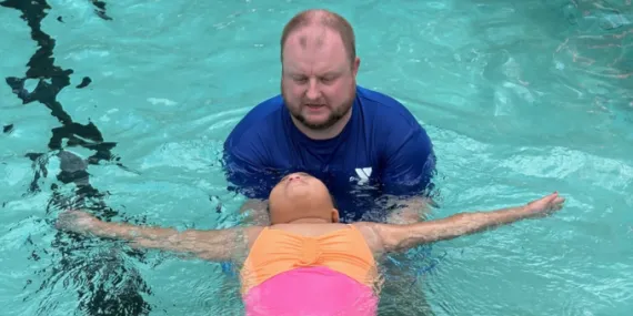 swim instructor teaching girl how to float on her back