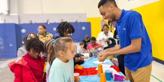 camp counselor helping children at a table