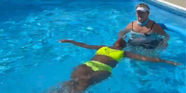 swim instructor swimming with an adult on her back