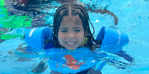 child in the pool swimming with floaties