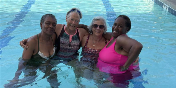 a group of men and women in the pool hugging