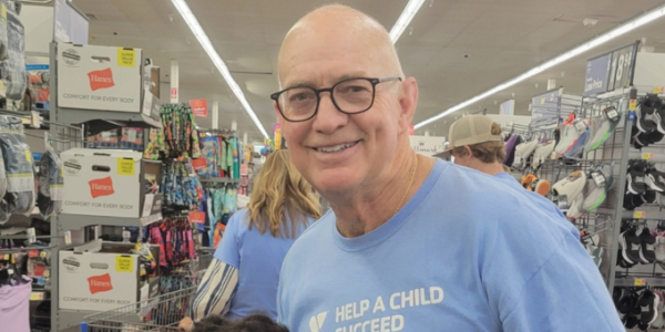 A bald headed man wearing glasses smiling.