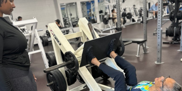 a female coach looking over a female participant on a leg press
