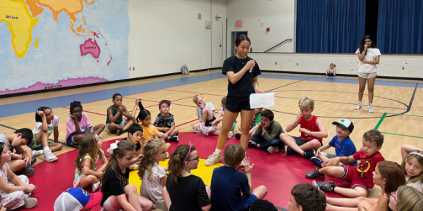 young teen reading to a group of children sitting on the floor