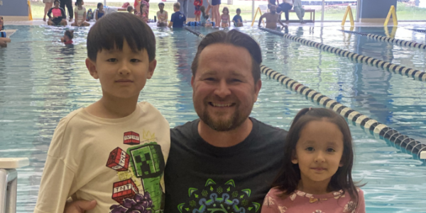 dad and son and daughter hugging on a pool deck