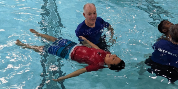 swim instructor teaching a boy to float on their back