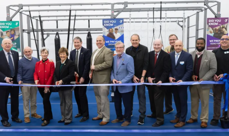 group of people cutting a blue ribbon