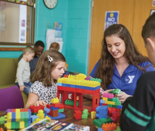 A volunteer playing building blocks with kids.