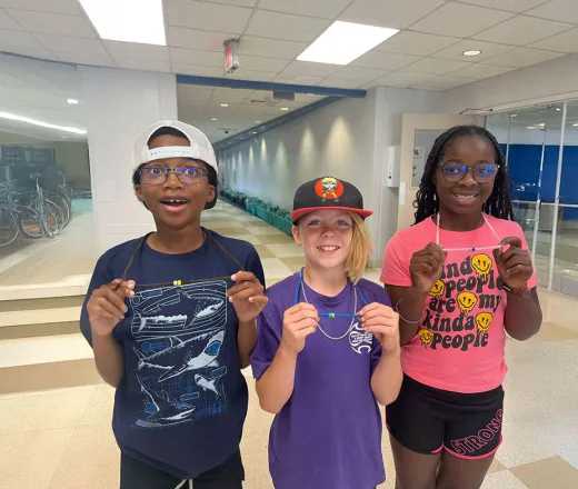 three kids holding up items from art project