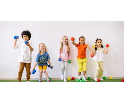 five children standing infront of a wall holding different colored balls