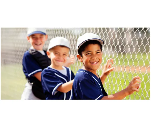 three kids in a baseball uniform holding on to a fence smiling