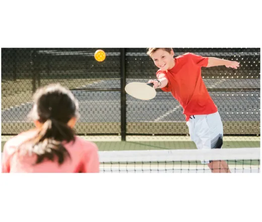 two kids playing pickleball