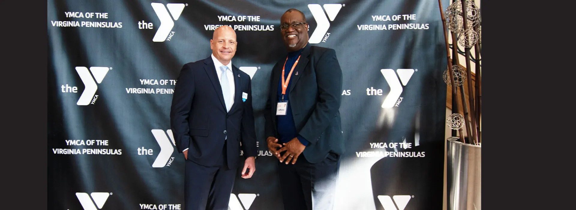 Two people taking picture in front of YMCA banner.